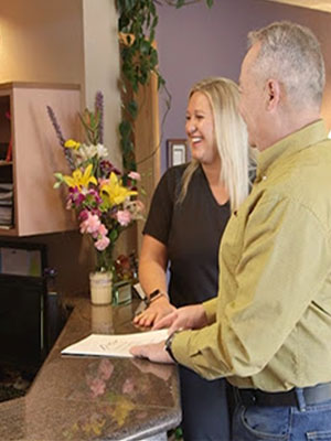 happy patient talking to staff at the front desk