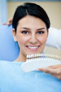 dentist matching color of patient's teeth with sample colors