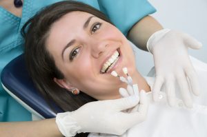 dentist matching a patient's tooth color to samples